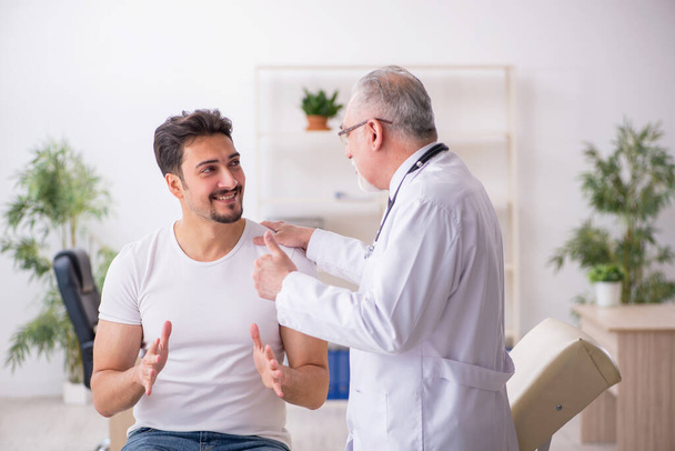 Jeune patient de sexe masculin visitant un vieux médecin - Photo, image