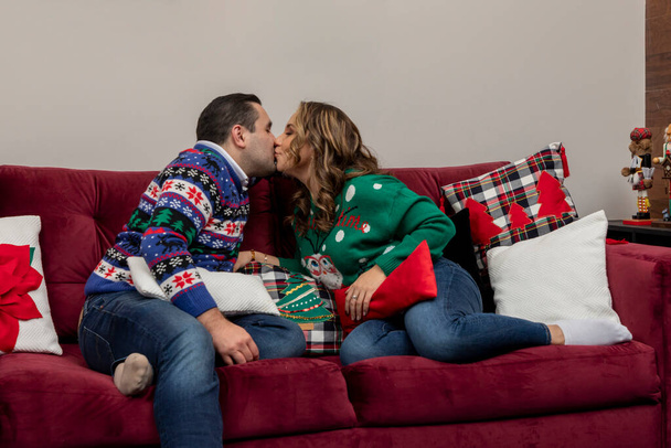 Ζευγάρι φιλιά στο σαλόνι τους τη νύχτα των Χριστουγέννων, μαξιλάρια με χριστουγεννιάτικο σχέδιο - Φωτογραφία, εικόνα