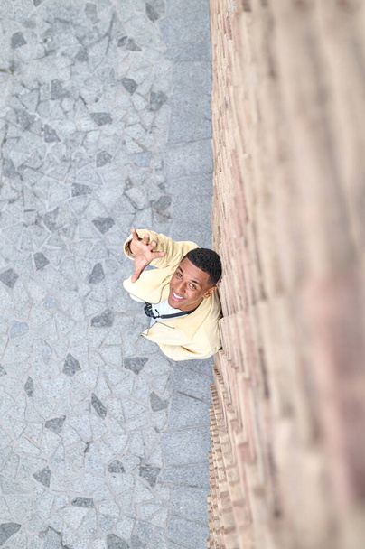Top view of young man looking up and his arm stretched - Fotoğraf, Görsel