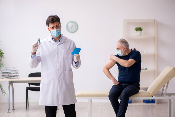 Old male patient visiting young male doctor in vaccination conce - 写真・画像