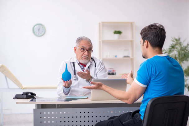 Jovem paciente masculino visitando velho médico gastroenterologista masculino - Foto, Imagem