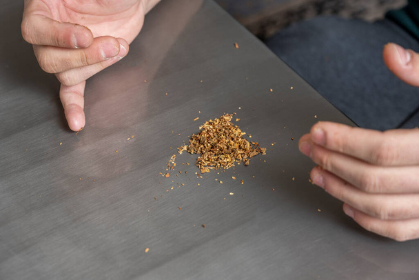 Hands preparing blond tobacco mix for smoking with rolling paper - 写真・画像
