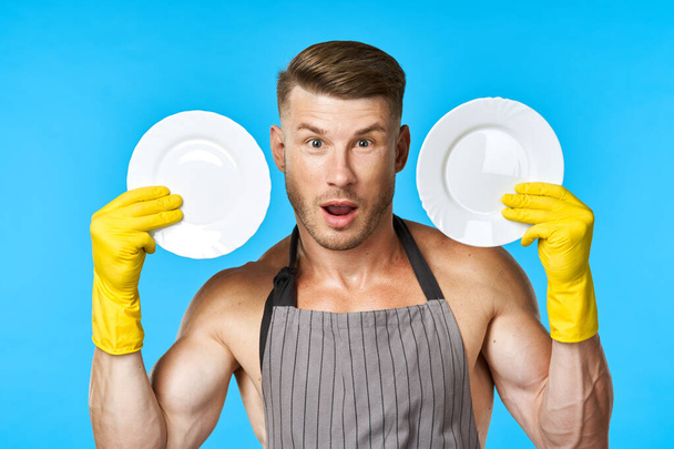 Cheerful man in aprons washing dishes housework blue background - Valokuva, kuva