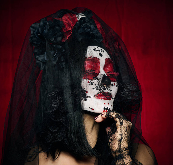 piękna kobieta z cukrem makijaż czaszki z wieńcem kwiatów na głowie, czerwone tło - Zdjęcie, obraz