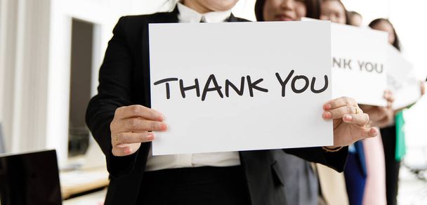 Group of businesspeople join together greeting and hold thank you word for sign of thankfulness to someone in modern office. Idea for good teamwork feeling declaration and support for colleagues. - Foto, imagen