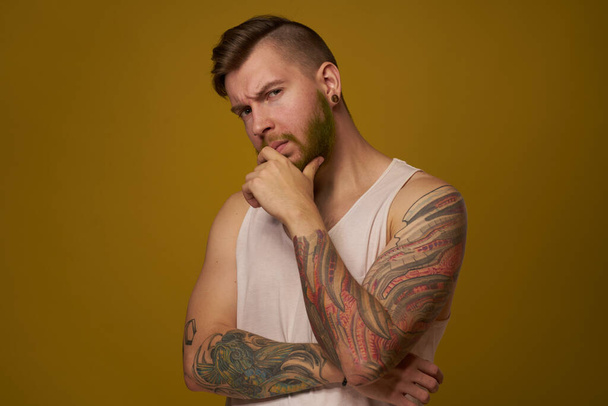 bearded man in white t-shirt with tattoos on his arms posing serious look - Zdjęcie, obraz