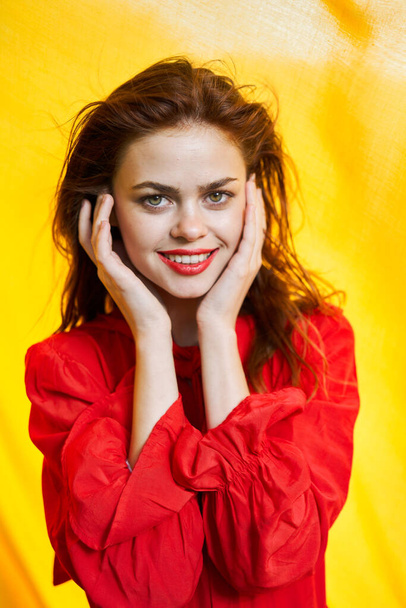 smiling woman in red dress posing yellow background - Foto, imagen
