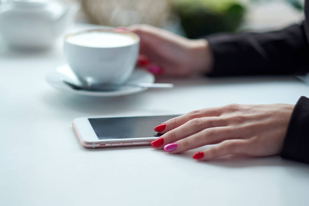 Woman hands with smart phone, headphones and cup of tea. For Graphic display montage - Photo, image