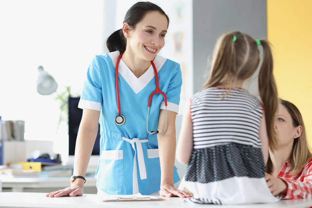 Sorridente pediatra professionista parlare con la giovane ragazza paziente carino su appuntamento - Foto, immagini