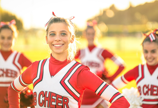 Portret van een gelukkige jonge cheerleader in actie in openlucht - groep van vriendinnen tijdens cheerleading sport opleiding op middelbare school - Foto, afbeelding