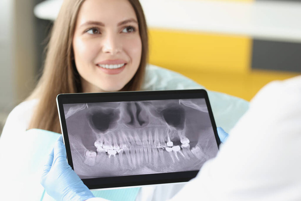 Οδοντιατρική γνωμάτευση σε κλινική και ιατρό εξέταση δοντιών ακτινογραφία σε ψηφιακή οθόνη tablet - Φωτογραφία, εικόνα