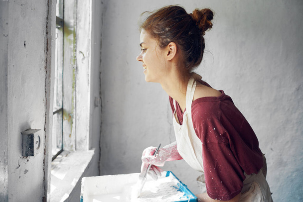 woman painter makes home repairs near window interior - Photo, Image