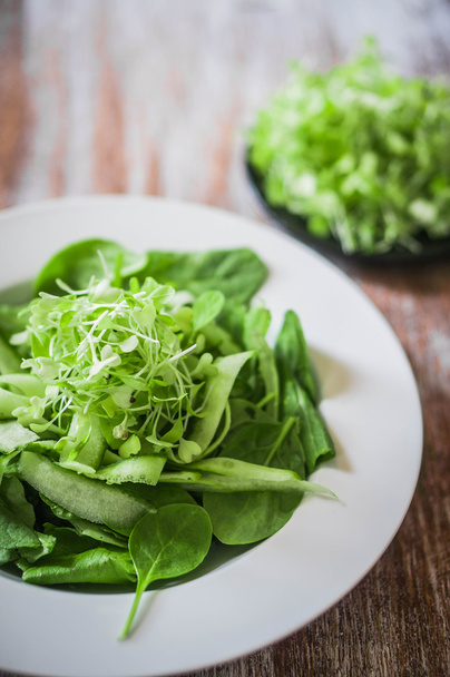 Salad with spinach,cucumber and microgreens on wooden background - Foto, afbeelding
