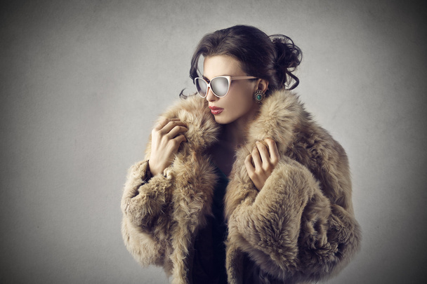 Elegant girl wearing sunglasses and a fur coat - Foto, Imagen