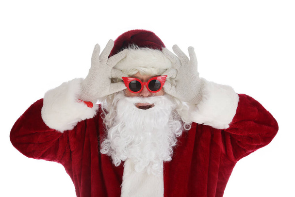 Santa Claus models Sun Glasses. Santa Claus poses while wearing fashion sunglasses. Isolated on white. Christmas Fun with Santa Claus showing off Sunglasses as gifts. - Фото, зображення