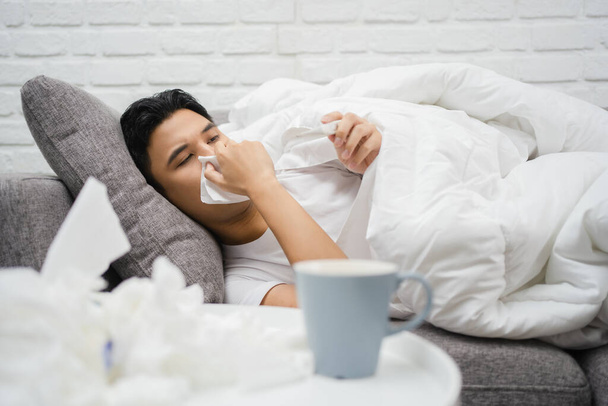 Hombre enfermo con fiebre acostado en el sofá en casa. - Foto, Imagen