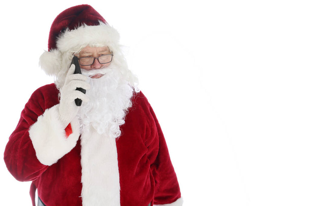 Ο Άγιος Βασίλης χρησιμοποιεί το κινητό του. Santa χρησιμοποιεί το κινητό του στο κείμενο και να στείλετε και να λάβει τηλεφωνικές κλήσεις κατά τη διάρκεια της πολυάσχολης εποχής του. Η Σάντα λατρεύει την τεχνολογία. Καλά Χριστούγεννα. Καλές γιορτές.. - Φωτογραφία, εικόνα