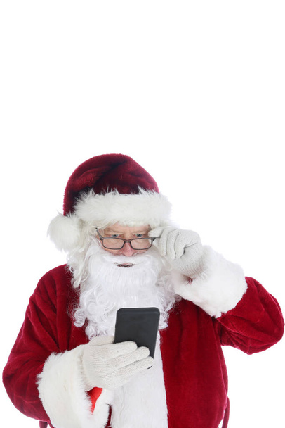 Der Weihnachtsmann benutzt sein Mobiltelefon. Der Weihnachtsmann benutzt sein Handy, um während seiner geschäftigen Zeit SMS zu schreiben, zu senden und anzurufen. Der Weihnachtsmann liebt Technologie. Frohe Weihnachten. Frohe Feiertage. - Foto, Bild