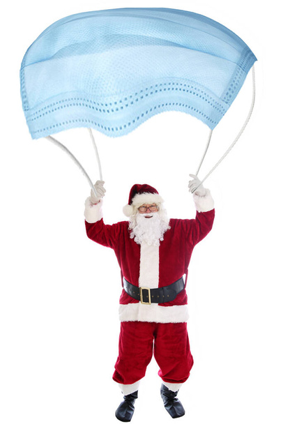 Papai Noel Paraquedas com uma máscara facial Covid-19. Humor de Natal. Isolado em branco. Papai Noel usa uma máscara facial Coronavirus para um paraquedas. Feliz Natal. Paraquedismo Papai Noel com um Paraquedas - Foto, Imagem