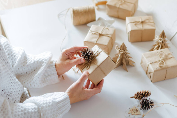 女性の手はクリスマスの包装のギフトのために準備している。冬の休暇の準備創造的な贈り物の装飾を作る - 写真・画像