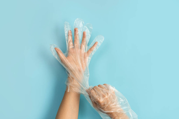 Hand wearing disposable plastic glove isolated on color background - Valokuva, kuva