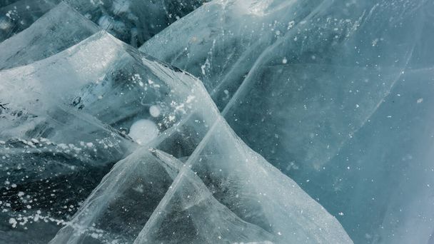 Ghiaccio trasparente turchese di un lago ghiacciato. Primo piano. A schermo intero. Sono visibili crepe profonde, bolle di gas metano congelato. Baikal - Foto, immagini