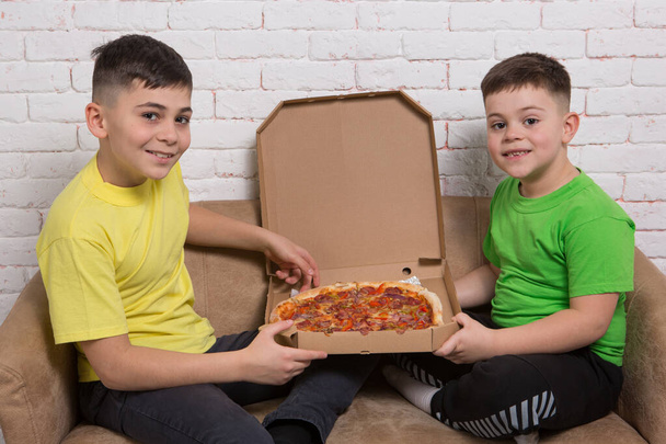 dois meninos felizes segurando pizza, sentado no sofá, sorrindo, delicioso almoço, conceito - Foto, Imagem