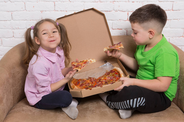 χαρούμενα παιδιά, αγόρια και κορίτσια, διασκεδάζουν τρώγοντας ιταλική πίτσα, γεμίζοντας το στόμα γεμάτο, χαμογελαστό, concept - Φωτογραφία, εικόνα