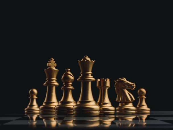 Набор золотых шахматных фигур элемент, король, королева ладья, епископ, рыцарь, пешка, стоящий на шахматной доске на темном фоне. Лидерство, командная работа, партнерство, планирование и концепция бизнес-стратегии. - Фото, изображение