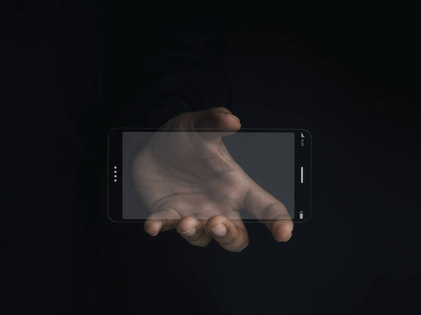 Futuristic transparent glass phone Technology. Super slim transparent future smartphone with horizontal mock-up blank screen in hand on dark background. - Foto, Imagem