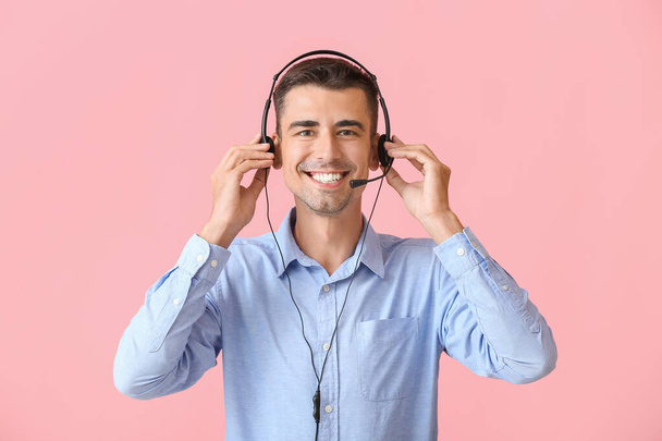 Άντρας σύμβουλος του τηλεφωνικού κέντρου με ακουστικά σε ροζ φόντο - Φωτογραφία, εικόνα