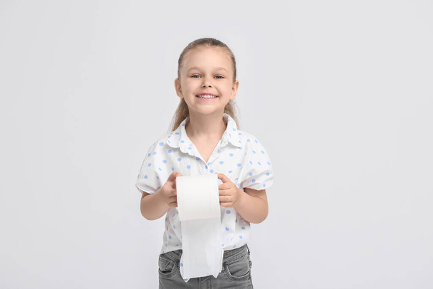 Little girl with toilet paper on light background - Фото, изображение