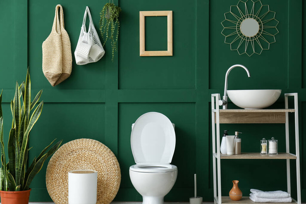 Interieur van toilet met toilet, wastafel en groene wand - Foto, afbeelding