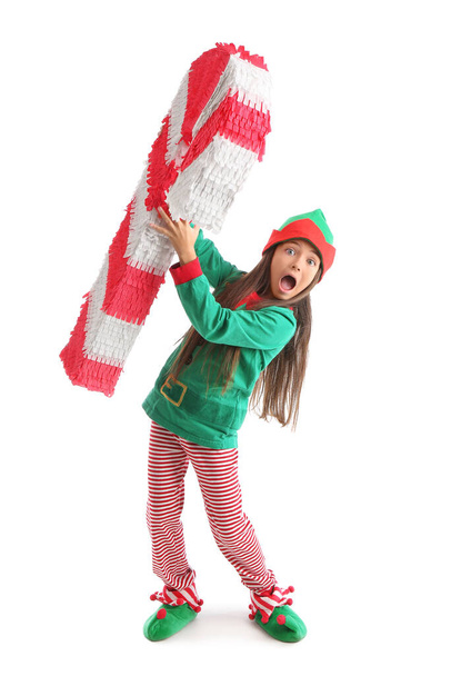 Beyaz arka planda şeker kamışı pinyatasıyla Elf gibi giyinmiş küçük bir kız. - Fotoğraf, Görsel