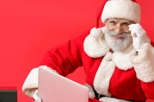 Santa Claus z nowoczesnym laptopem na tle koloru - Zdjęcie, obraz