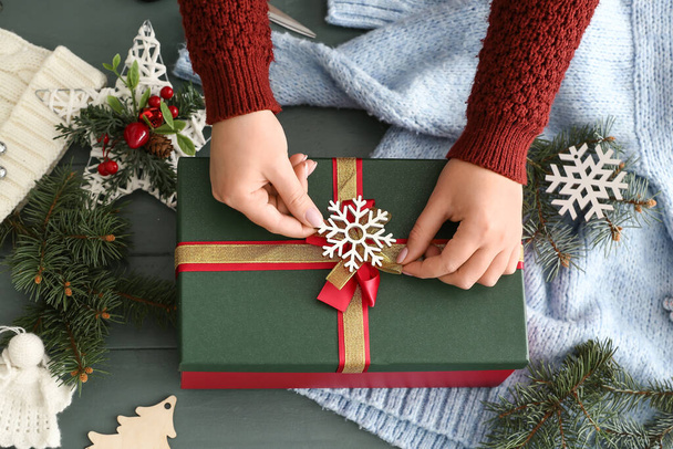 Woman decorating Christmas gift box on grey wooden background - Valokuva, kuva