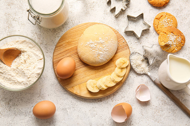 Tavola di legno con pasta fresca e ingredienti per preparare biscotti fatti in casa su sfondo chiaro - Foto, immagini