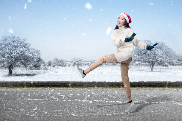 Asian woman with winter gloves and Santa hat standing on the street with snowfall background - Φωτογραφία, εικόνα