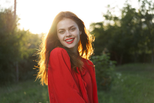 cheerful woman in a red dress in a field outdoors fresh air - Foto, afbeelding