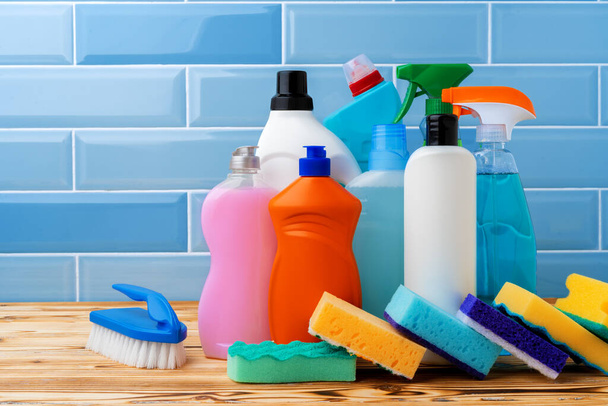 Household detergents and cleaning tools against blue tile background - Foto, imagen