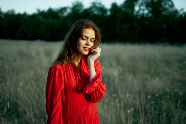 cute red-haired woman in red dress in field nature summer - Foto, Imagem