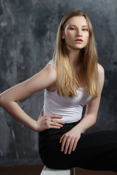 Nice blonde girl in a white shirt on a gray background. - Photo, Image