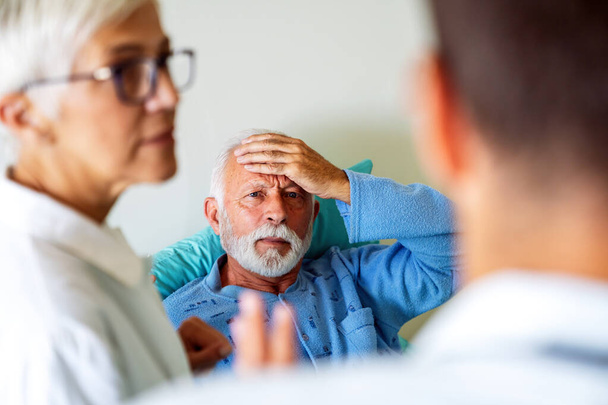 Az orvos egy idős férfi beteggel beszél a kórházi ágyban, aki lábadozik a betegségből. Egészségügyi ellátás, coronavirus, emberek koncepciója. - Fotó, kép