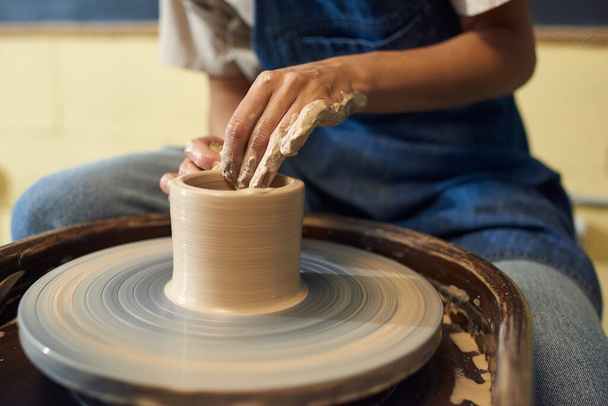 Mãos de oleiro fêmea jovem sentado por roda de cerâmica rotativa - Foto, Imagem