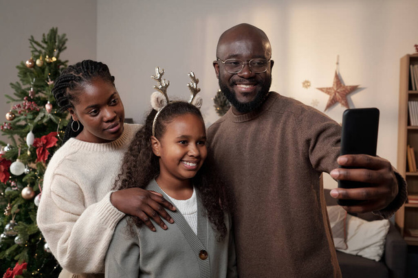 Onnellinen nuori perhe kolme tehdä selfie by joulukuusi - Valokuva, kuva