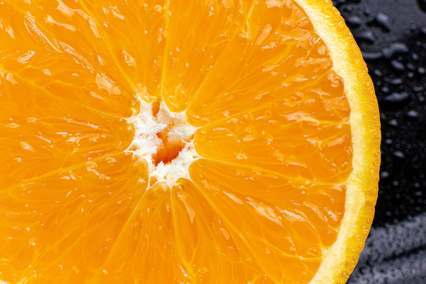 Orange slice. Half an orange. Cross section. Orange on a black background. - 写真・画像