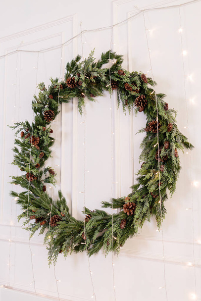 Decorations for the new year, a wreath of fir branches on the wall. Christmas decorative wreath in a cozy home - Photo, Image