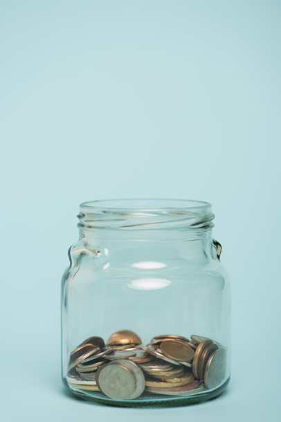 glazen pot met gouden en zilveren munten op blauwe achtergrond, anti-corruptie concept - Foto, afbeelding