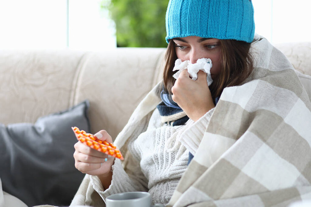 Mujer con resfriado se sienta en el sofá con pastillas y pañuelo - Foto, imagen