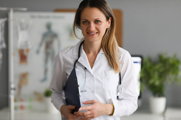 Young smiling female doctor holding clipboard closeup - 写真・画像